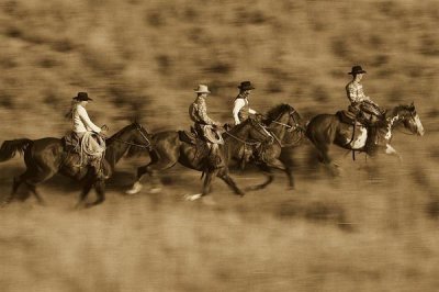 Konrad Wothe - Cowboys and a cowgirl riding Horses through field, Oregon - Sepia
