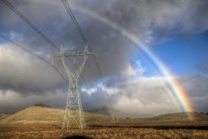 Colin Monteath - Powerlines, rainbow forms as evening sun lights up rain clouds, Canterbury, New Zealand