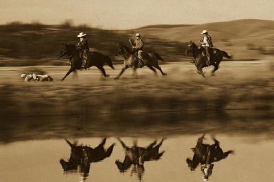 Konrad Wothe - Cowboys riding Horses with dogs running beside pond, Oregon - Sepia