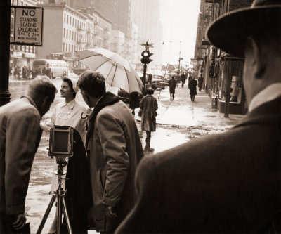 Angelo Rizzuto - Woman being photographed in the rain, New York City, 1954